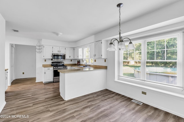 kitchen featuring white cabinetry, sink, stainless steel appliances, kitchen peninsula, and light hardwood / wood-style floors