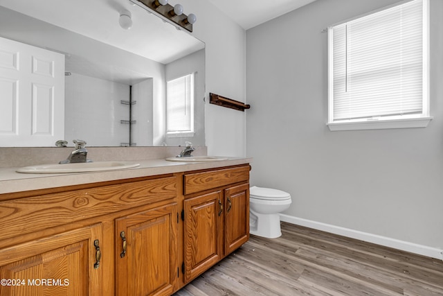 bathroom with wood-type flooring, vanity, a tile shower, and toilet