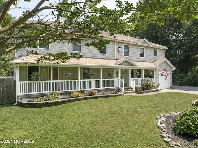 view of front of property featuring a front yard, a garage, and covered porch