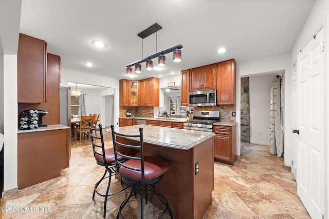 kitchen featuring a center island, hanging light fixtures, decorative backsplash, a breakfast bar, and appliances with stainless steel finishes