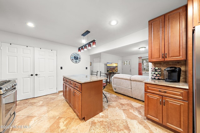 kitchen featuring a center island, stainless steel gas range, backsplash, decorative light fixtures, and a kitchen bar