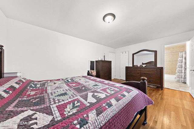 bedroom with hardwood / wood-style flooring, baseboard heating, and ensuite bathroom