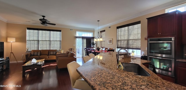 kitchen with pendant lighting, sink, double oven, dark hardwood / wood-style flooring, and dark stone counters