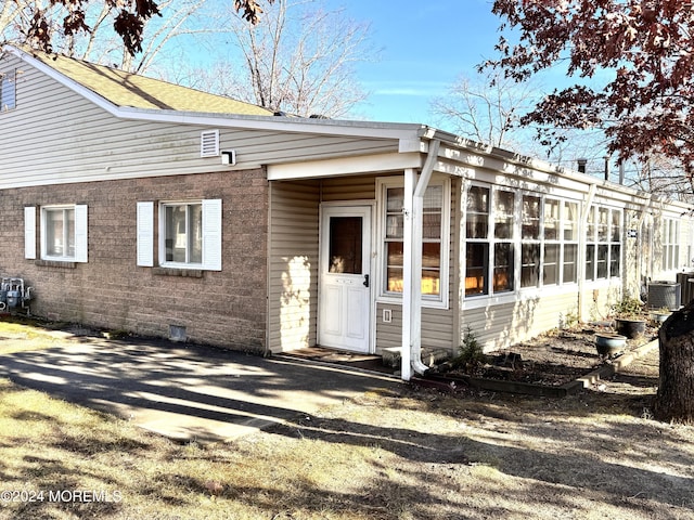 exterior space featuring central air condition unit and a sunroom