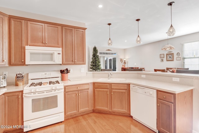 kitchen with decorative light fixtures, sink, light hardwood / wood-style floors, and white appliances