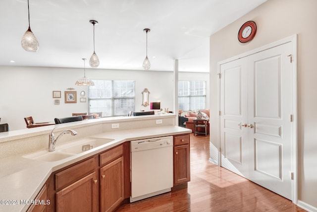 kitchen featuring sink, white dishwasher, pendant lighting, and light wood-type flooring