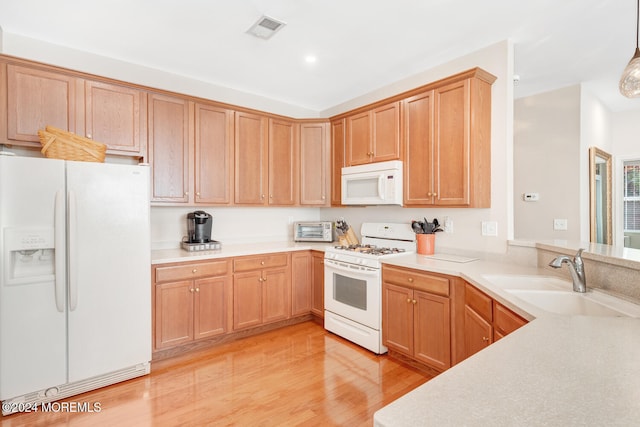 kitchen featuring sink, hanging light fixtures, white appliances, and light wood-type flooring