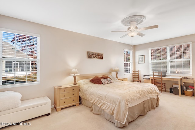 bedroom featuring light carpet, multiple windows, and ceiling fan