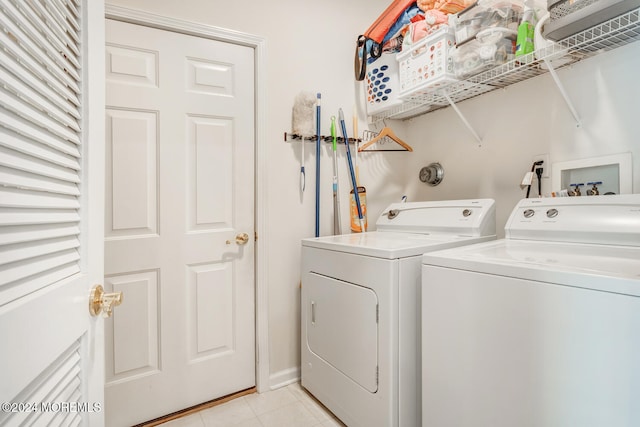 laundry area with separate washer and dryer and light tile patterned floors