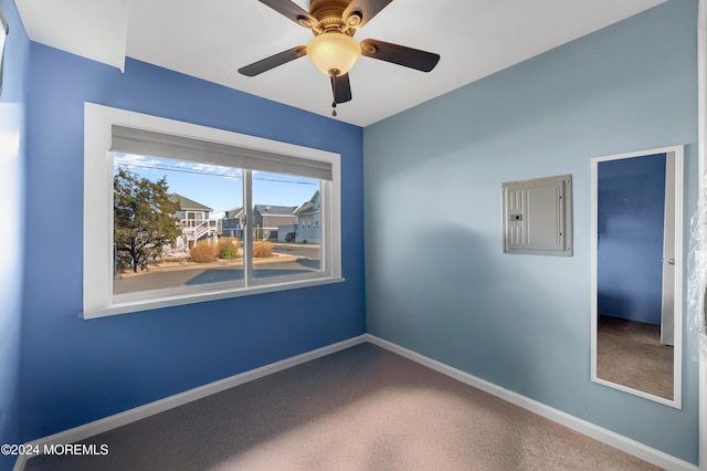 spare room featuring electric panel, ceiling fan, and carpet