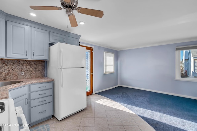 kitchen featuring tasteful backsplash, ornamental molding, white refrigerator, light tile patterned floors, and range