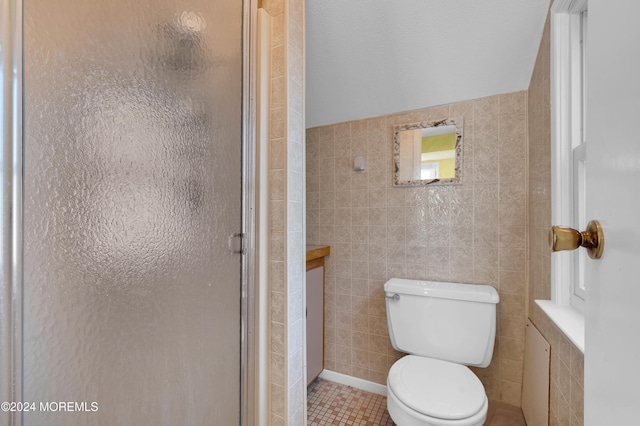 bathroom featuring tile patterned floors, toilet, a shower with shower door, and tile walls