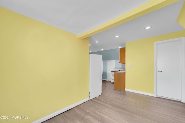 empty room featuring beam ceiling and light hardwood / wood-style flooring