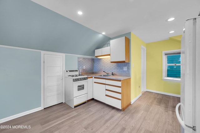 kitchen featuring white cabinetry, sink, vaulted ceiling, white appliances, and light wood-type flooring