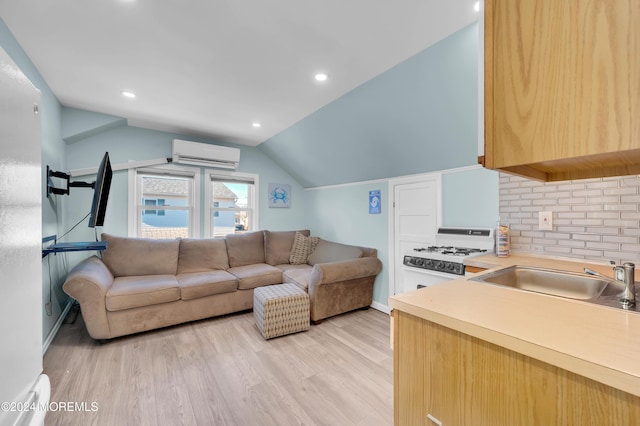 living room featuring vaulted ceiling, light hardwood / wood-style floors, a wall unit AC, and sink