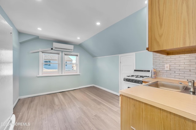 kitchen with lofted ceiling, an AC wall unit, sink, light hardwood / wood-style flooring, and white gas stove