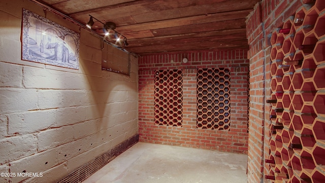 wine room with wood ceiling and brick wall