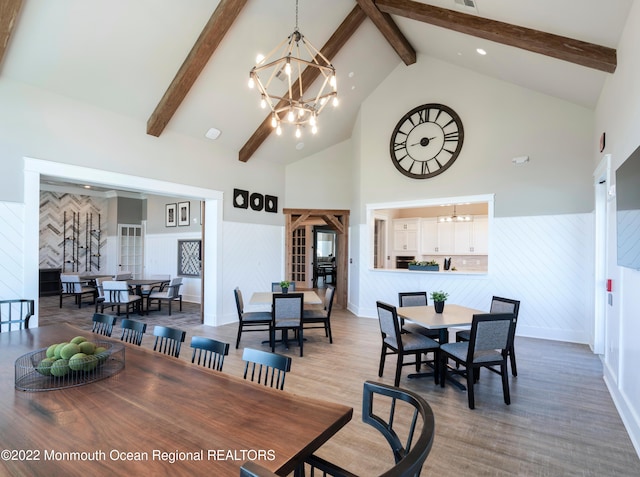 dining space with beam ceiling, wood-type flooring, high vaulted ceiling, and an inviting chandelier