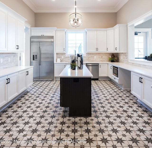 kitchen featuring white cabinets, crown molding, built in appliances, a chandelier, and a kitchen island