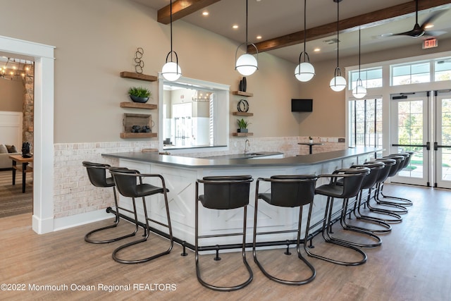 kitchen featuring a kitchen bar, kitchen peninsula, beam ceiling, pendant lighting, and hardwood / wood-style flooring