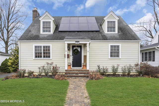 new england style home with a front yard and solar panels