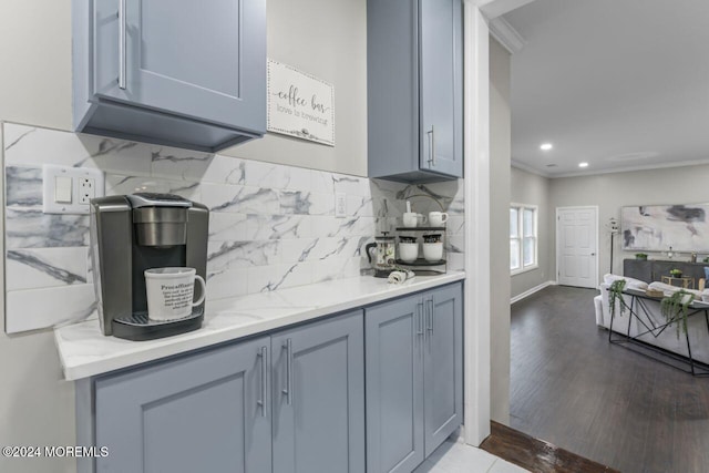 kitchen with gray cabinets, wood-type flooring, ornamental molding, and tasteful backsplash