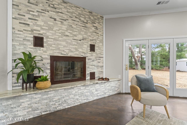 living room with hardwood / wood-style flooring, a stone fireplace, and crown molding