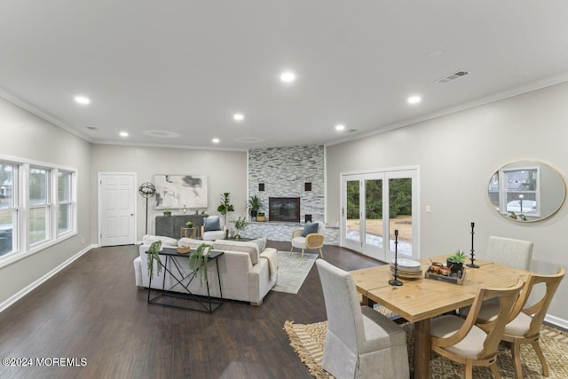 living room with dark hardwood / wood-style floors, a stone fireplace, and crown molding