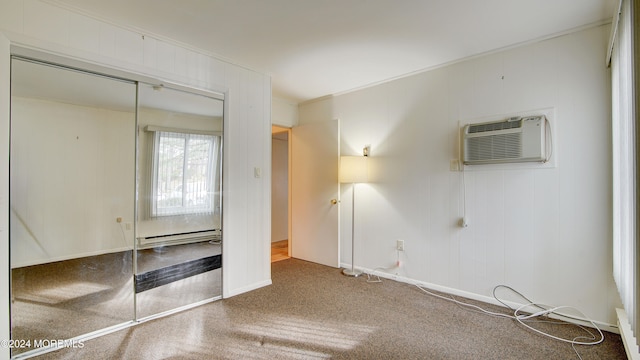 unfurnished bedroom with an AC wall unit, crown molding, a baseboard radiator, and a closet