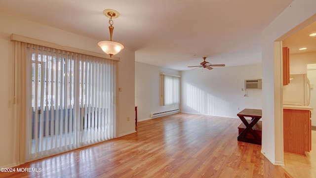 unfurnished room with a wall mounted air conditioner, ceiling fan, light hardwood / wood-style floors, and a baseboard heating unit