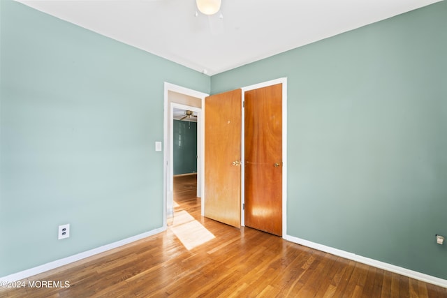 unfurnished bedroom featuring hardwood / wood-style flooring, a closet, and ceiling fan