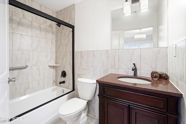 full bathroom featuring shower / bath combination with glass door, vanity, toilet, and tile walls