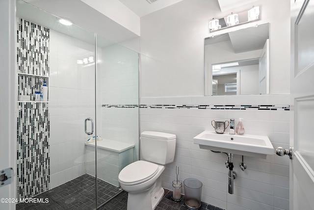 bathroom with sink, tile patterned flooring, toilet, a shower with door, and tile walls