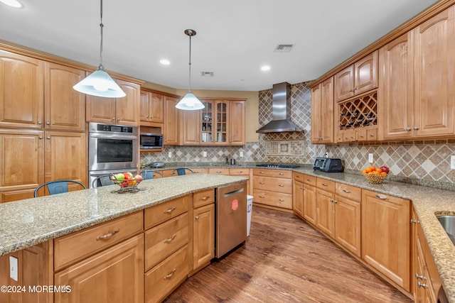 kitchen featuring light stone countertops, pendant lighting, wall chimney exhaust hood, and stainless steel appliances