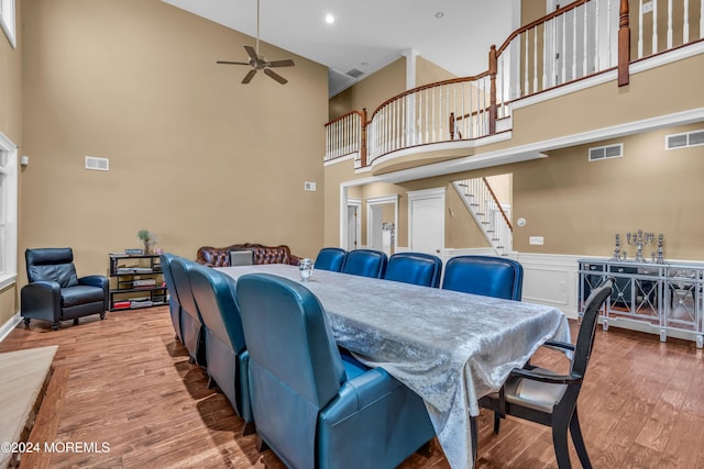 dining area with hardwood / wood-style floors, ceiling fan, and a high ceiling