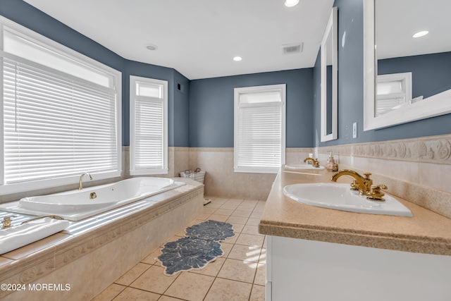 bathroom with tile patterned flooring, vanity, and a relaxing tiled tub