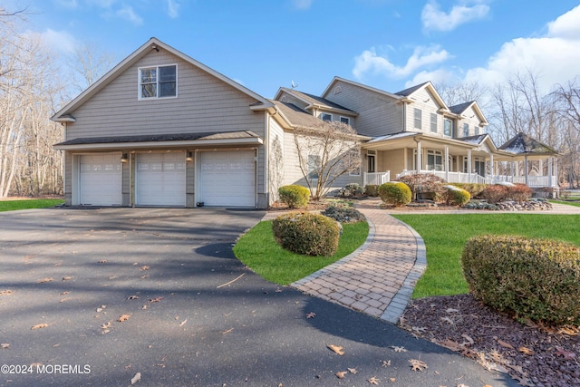 front of property with a porch, a garage, and a front lawn