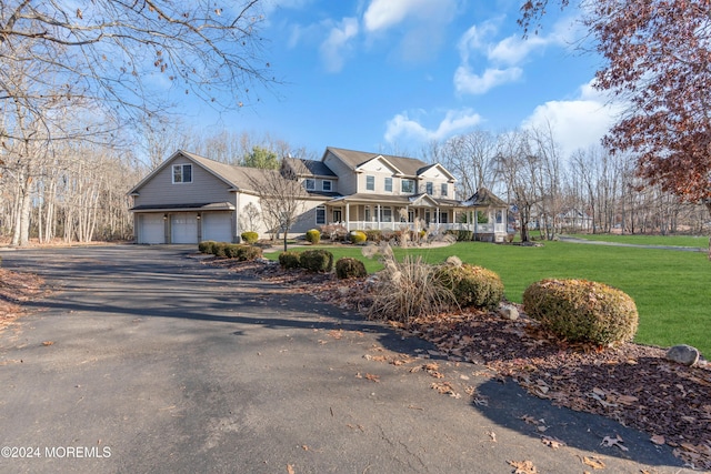 view of front of house featuring a porch, a garage, and a front lawn