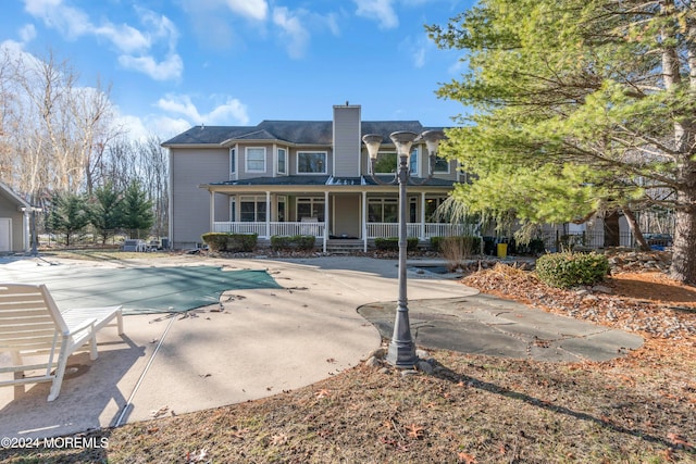 back of property with a patio and a covered pool