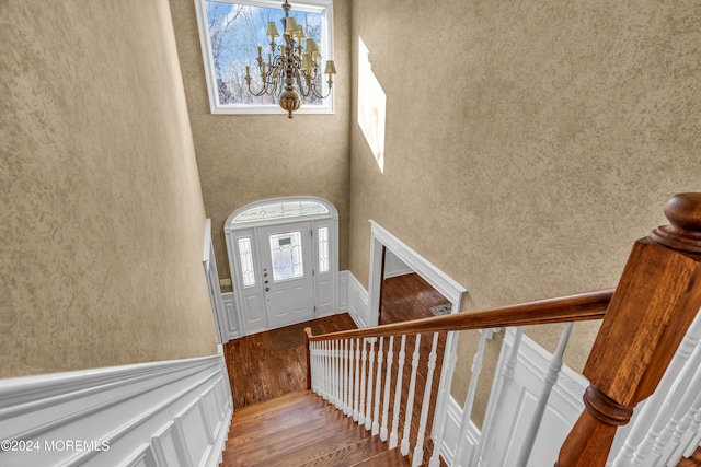 foyer with a high ceiling, hardwood / wood-style flooring, and an inviting chandelier