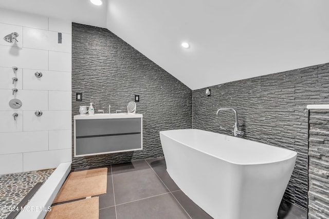 bathroom with vanity, vaulted ceiling, tile walls, independent shower and bath, and tile patterned flooring