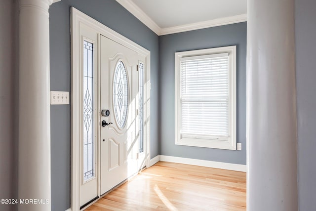 entrance foyer featuring light hardwood / wood-style flooring, ornate columns, and ornamental molding