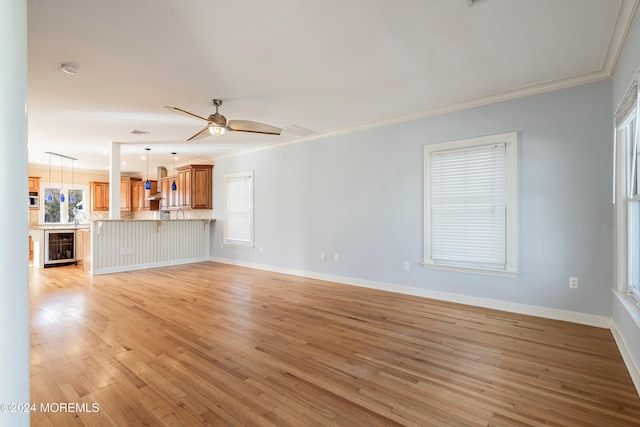 unfurnished living room featuring wine cooler, ceiling fan, light hardwood / wood-style floors, and ornamental molding