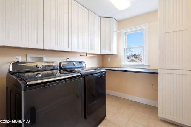 washroom featuring washer and dryer, cabinets, and light tile patterned floors