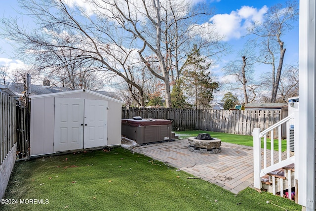 view of yard with a hot tub, a storage unit, a patio area, and a fire pit