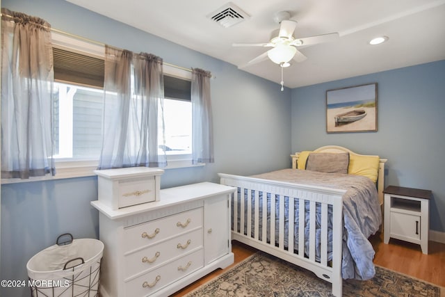 bedroom featuring ceiling fan, multiple windows, and dark hardwood / wood-style floors