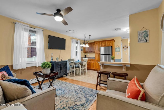 living room with ceiling fan, a baseboard heating unit, and light hardwood / wood-style flooring