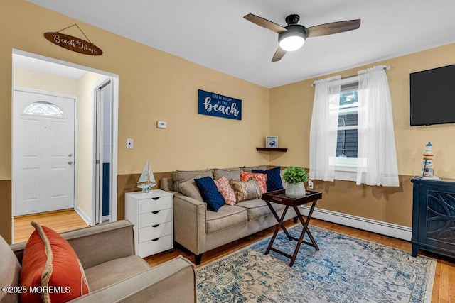 living room featuring ceiling fan, a baseboard heating unit, and light wood-type flooring