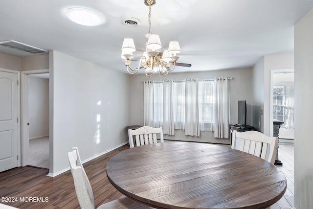 dining space with baseboard heating, a wealth of natural light, dark wood-type flooring, and a notable chandelier