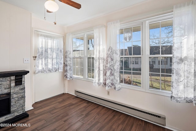 unfurnished sunroom featuring a fireplace, baseboard heating, and a wealth of natural light